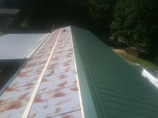 Old rusted panels beside newly installed green metal roofing — Wind Damage Roof Repair by Roofing Brothers in Garland